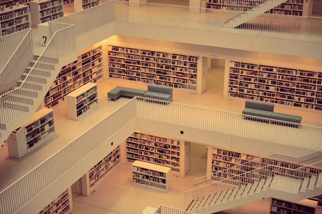 Quiet reading room of a library with rows of shelves